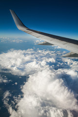 beautiful view from window porthole. wing of the plane on a background of clouds and blue sky. flight of airplane over city.