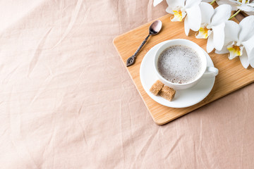 Cozy composition with a Cup of coffee on a tray with sugar on a pastel coffee blanket Flat lay, top view.