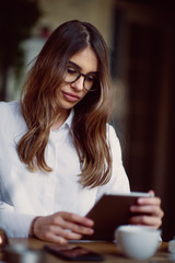 Young modern woman sitting in cafe and using tablet.