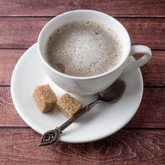 White Cup and saucer Coffee with milk foam and cane sugar cinnamon Anise