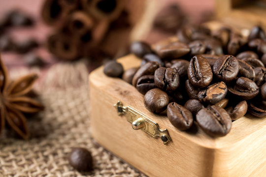 Coffee beans in a wooden box with cinnamon sticks and star anise on burlap napkins