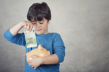 niño sonriente con un billete de euro y una hucha cerdito