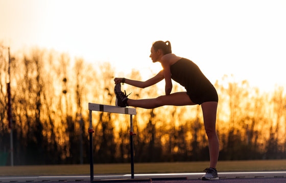 Athletic Woman Stretching On The Hurdle, Stadium Running Track