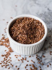 Flax seeds in white ramekin on marble board