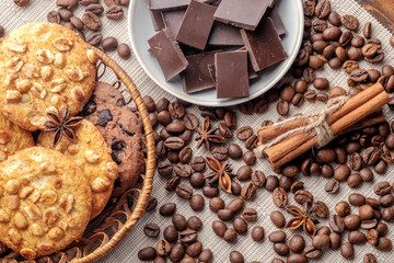 Chocolate chips cookies and peanut cookies in wicker basket and saucer with pieces of chocolate. Close-up view.