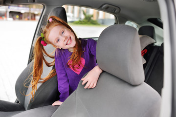 baby cute red-haired girl smiling in car salon