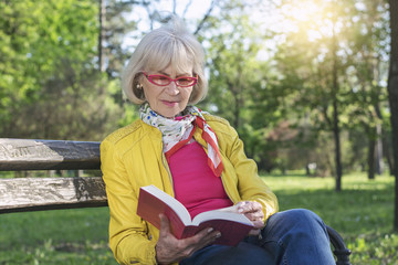 Senior woman reading a book outdoors