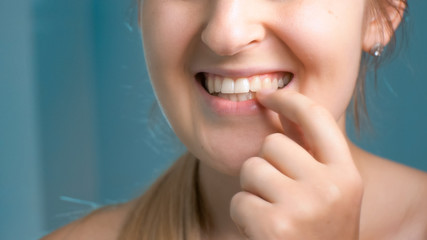 Closeup image of young woman checking her teeth at bathroom