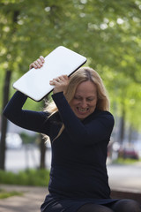 Very angry woman breaks the laptop. - obrazy, fototapety, plakaty