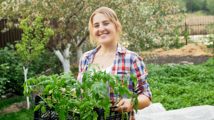 Beautiful smiling woman with tomato seedlings in garden
