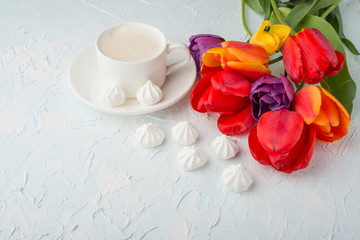Multicolored tulips with coffee and bise on light background, top view, with empty space for writing or advertising