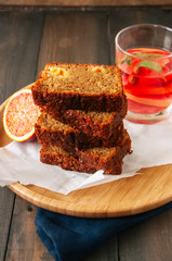 Slices of blood orange vegetarian pound cake on a wire rack. Wooden background.