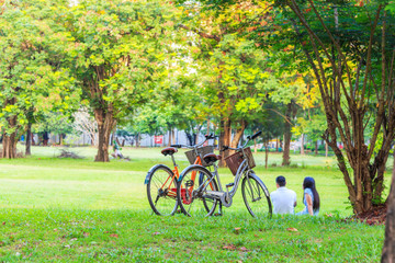 Couple bicycle on the lawn with couple asian people resting on the grass blurry background.