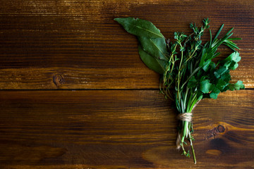 Bouquet garni with bay leaves and fresh herbs de provence on dark wooden background