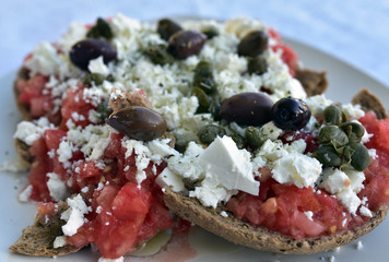 Traditional Greek, Cretan, barley rusk bread accompanied by fresh tomatoes, white cheese and black olives - obrazy, fototapety, plakaty