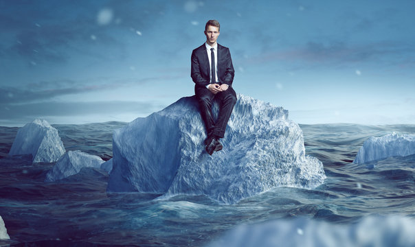 Geschäftsmann sitzt auf Eisberg im Meer