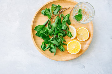 Ingredients for moroccan tea or infused water. Mint leaves slices of lemon on a wooden plate. White background. Top view.