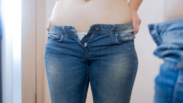 Closeup photo of young woman looking at her big belly in mirror