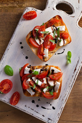 Caprese Bruschetta. Tomatoes, basil, mozzarella cheese with balsamic reduction drizzle on toast. Antipasto - starter dish. View from above, top