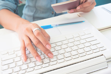 Woman's hands using laptop computer and holding passport book, Business and Travel concept