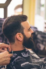 Bearded man sitting in barbershop. Profile view.