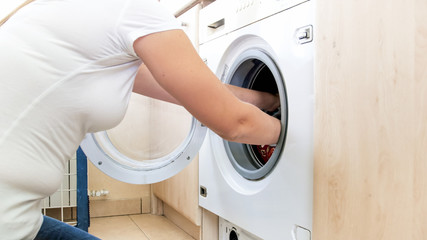 Fototapeta na wymiar Closeup photo of female hands taking clothes out of washing machine