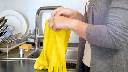 Closeup image of young woman holding yellow latex gloves