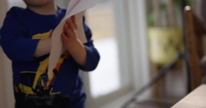 Toddler walking around with stack of paper in hands