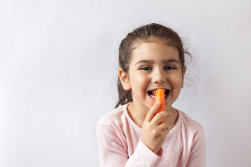 Happy little child girl eating fresh vegetables. Isolated portrait on white background. Healthy teeth.