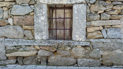 Fototapeta na wymiar Ventana con barrotes en una fachada de casa de piedra