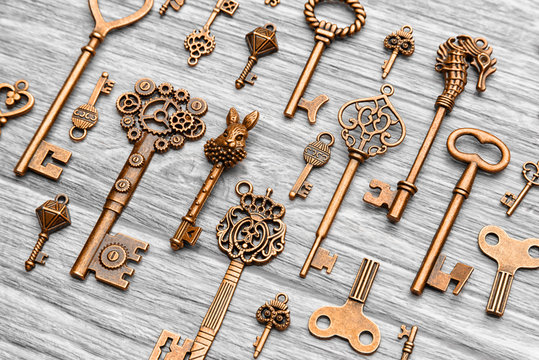 Many different vintage keys on a light wooden background