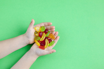 Child with a handful of candies on a green background