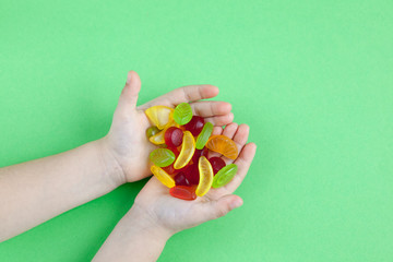 Child with a handful of candies on a green background