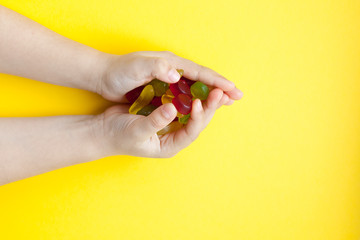 Child with a handful of candies on a yellow background