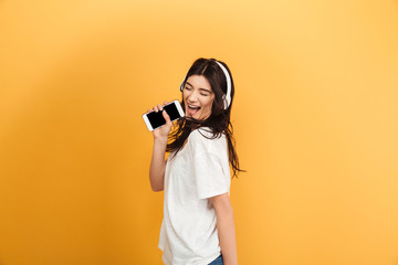 Amazing happy cute young pretty woman listening music with headphones singing in phone.
