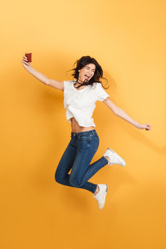 Emotional woman jumping make selfie by mobile phone.