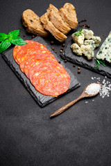 Slice of Roquefort cheese and chorizo sausage on stone serving board