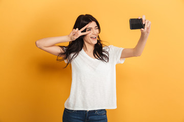 Cute young pretty woman make selfie with peace gesture by mobile phone.