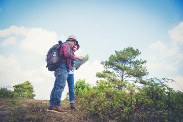 Young couple hiking on the mountain with backpack on peak of mountain, looking a map.