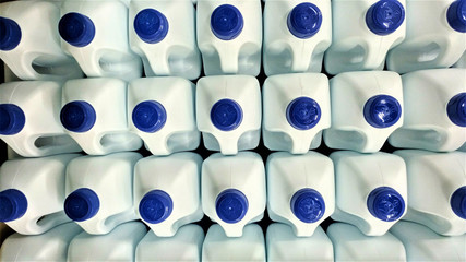 Botellas blancas de plástico con tapón azul apiladas para su transporte