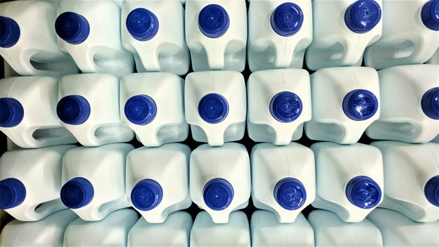 Botellas blancas de pl&aacute;stico con tap&oacute;n azul apiladas para su transporte