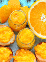 Bright homemade orange jam. Small jars with orange jam. Toast with orange jam. Bright yellow jam. Useful breakfast with citrus fruits.