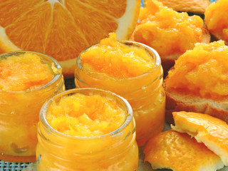 Fototapeta na wymiar Bright homemade orange jam. Small jars with orange jam. Toast with orange jam. Bright yellow jam. Useful breakfast with citrus fruits