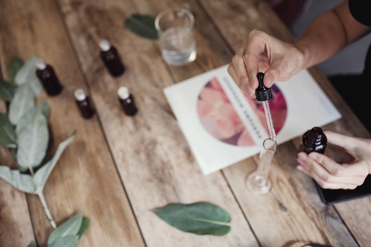 High angle view of woman using pipette for mixing liquid in test tube at perfume workshop