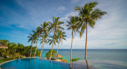 Outdoor swimming pool in a tropical country Philippines with palm trees. Evening time
