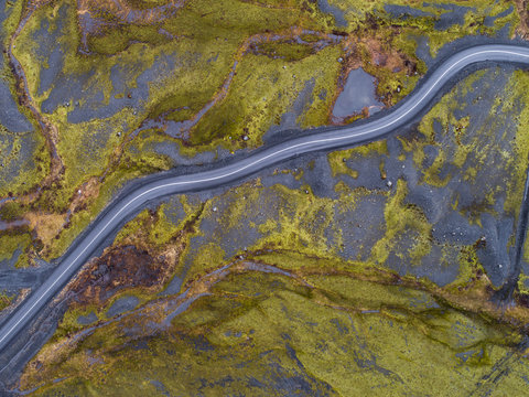 Aerial View Of A Road Crossing Volcanic And Green Icelandic Terrain Seen Directly Above