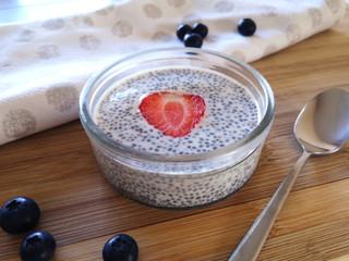 Jar with chia pudding with slice of strawberry and blueberries the wooden table