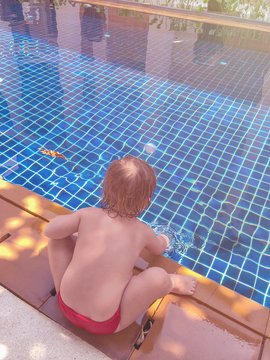 A Small Child Plays With Water In The Pool. Lack Of Parental Attention, Danger. Sunny Day