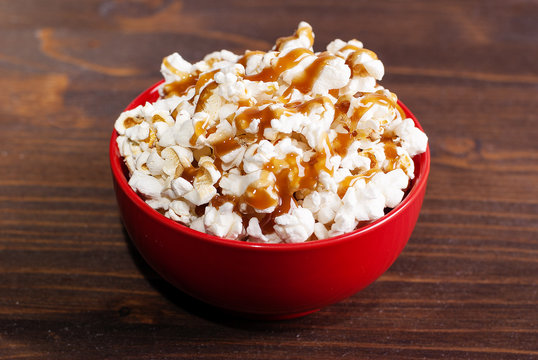 Popcorn In A Red Bowl Of Poured Caramel, On A Dark Table