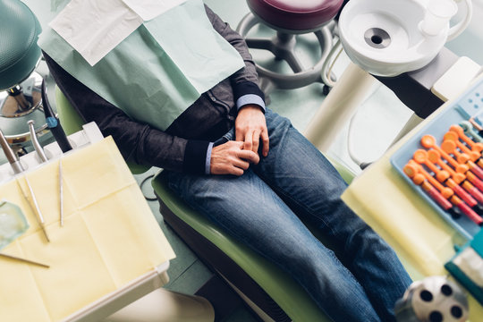 Male patient in dentist chair, mid section, elevated view